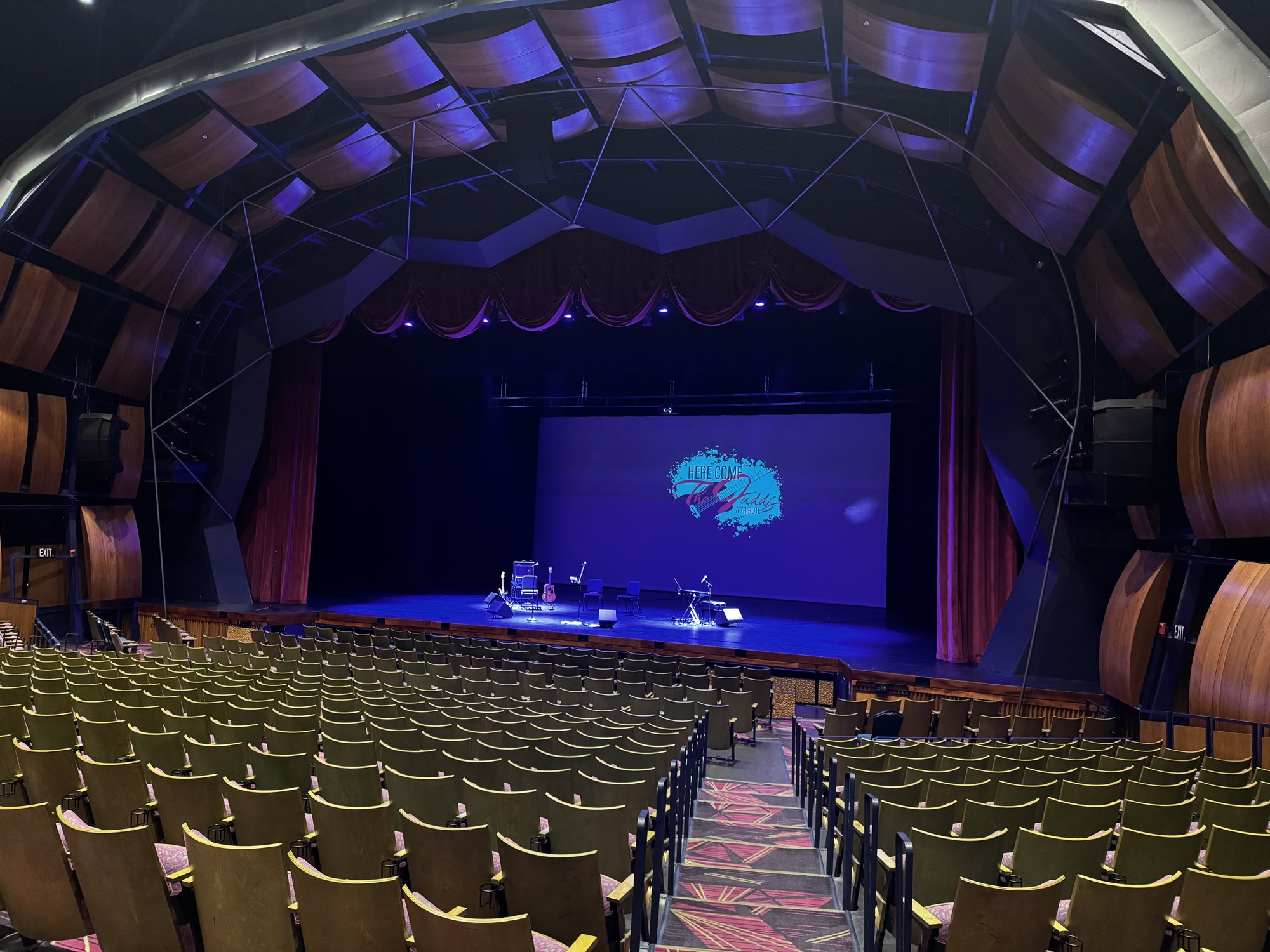 Large auditorium with the Here Come The Judds logo on the screen